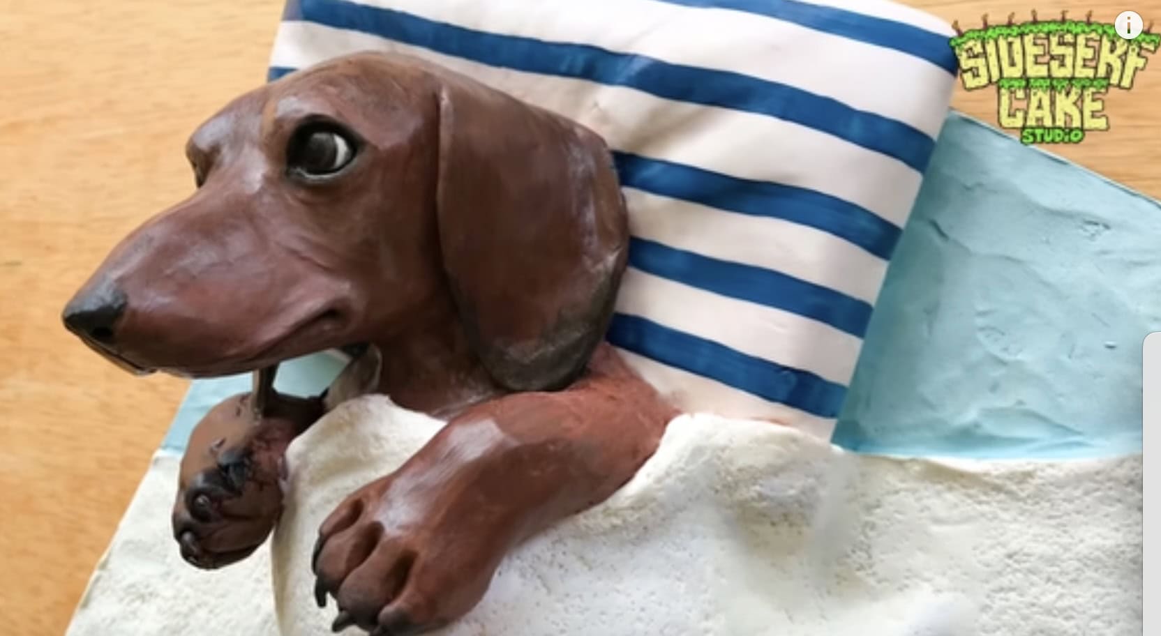 Realistic cake in the shape of a dachshund tucked into bed.